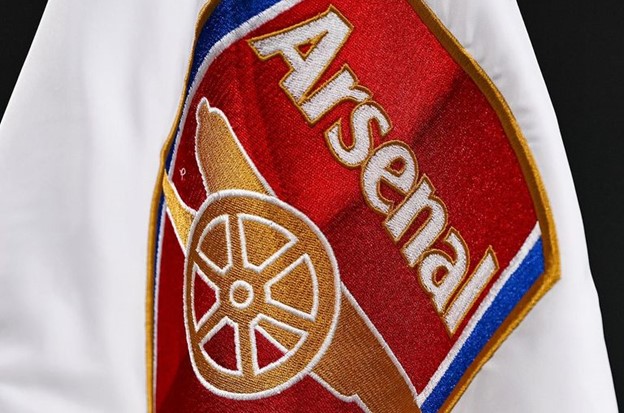  A close-up view of the Arsenal logo embroidered on a white fabric.