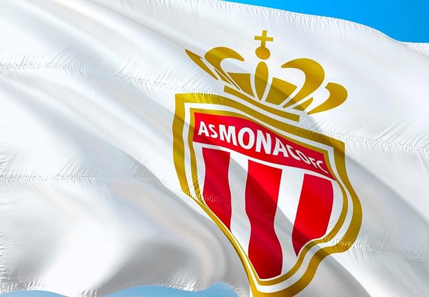 AS Monaco FC logo on a flag, featuring a red and white striped shield, crowned with a gold emblem.
